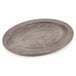 A Lodge oval wood underliner with a walnut finish under a round wooden plate on a table.