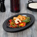 A black Lodge cast iron fajita skillet with food on it on a table.