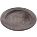 A Lodge round wood underliner with a walnut finish under a wooden plate with a round edge.