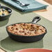 A small pre-seasoned cast iron skillet with a handle, shown containing a baked dessert.