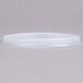 A translucent plastic lid with a straw slot on a white surface.