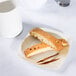 A close up of a Fineline ivory plastic dessert plate with food on a table.