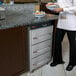 A woman in a white shirt using a Hatco drawer warmer to hold bread on a tray.