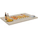 A table with a Hatco Glo-Ray heated stone warmer shelf holding food on it.