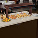 A Hatco Bermuda Sand heated stone shelf built into a hotel buffet counter filled with food.