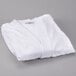 A pack of white Oxford velour kimono style bath robes folded on a gray surface.
