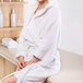A woman in a white Oxford Terry kimono-style bath robe sitting in a spa room.