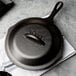 A black Lodge cast iron skillet with a lid on a table.