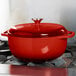 A Lodge Island Spice Red enameled cast iron Dutch oven on a stove.