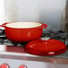 A Lodge Island Spice Red enameled cast iron dutch oven on a stove.