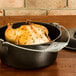A chicken in a Lodge cast iron Dutch oven on a wooden table.