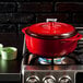 A Lodge Island Spice red enameled cast iron Dutch oven on a stove.