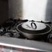 A Lodge cast iron skillet with a lid on a stove top.