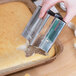 A person using an Ateco stainless steel cutter to cut a cake.