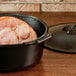 A Lodge Pro-Logic cast iron Dutch oven with a cooked ham inside.
