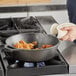 A person cooking chicken in a Lodge cast iron deep skillet on a stove.