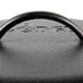 A close-up of a black cast iron Lodge cover with a handle.