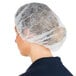 A woman wearing a white Chef Revival disposable polypropylene hair net.