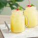 A glass jar of Del Monte Pineapple Juice with a yellow liquid and a cherry on top.