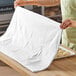 A large white 100% cotton flour sack towel being used in a kitchen setting.