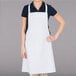 A woman wearing a white Chef Revival bib apron.