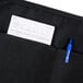 A black Chef Revival waist apron with a receipt and pen in the pockets.