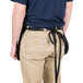 A man wearing a black Chef Revival waist apron with khaki pants.