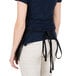 A woman wearing a Chef Revival black waist apron with 3 pockets.