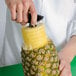 A hand using the Vacu Vin 3-in-1 Pineapple Corer/Slicer/Peeler to cut and peel a pineapple