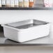 A white Carlisle Coldmaster pan in a metal shelf.