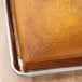 A rectangular brown cake in a Baker's Mark full-size sheet pan extender.