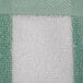 A close up of a mint green and white striped Oxford pool towel.