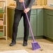 A person sweeping the floor with a Carlisle Sparta Duo-Sweep broom.