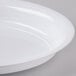 A close up of a Fineline white plastic deep oval bowl with a rim.