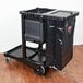 A black Rubbermaid janitor cart with black bag inside.