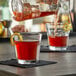 A person pouring a drink into an Anchor Hocking New Orleans Rocks glass on a table in a cocktail bar.