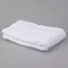 A folded white Oxford Regale bath towel on a gray surface.