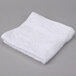 A white Oxford Regale wash cloth with dobby border and hem on a gray surface.