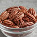 A bowl of Jr. Mammoth Raw Pecan Halves on a table.