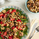 A bowl of salad with strawberries and Raw Walnut Halves and Pieces.