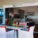 A white Bromic Heating Tungsten Smart-Heat outdoor patio heater next to a table with chairs and a plant.