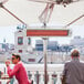 Two men sitting at a table under a Bromic Heating outdoor patio heater.