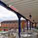 A white Bromic Heating Tungsten Smart-Heat electric patio heater over a white table and chairs.