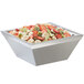 A Cal-Mil stainless steel square bowl filled with fruit on a counter.