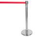 A silver metal Aarco crowd control stanchion with a red retractable belt.