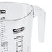 A clear measuring cup with a handle and black text.