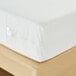 A white Bargoose Elite zippered mattress cover on a king mattress on a wooden surface.