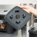 A hand holding a black square Waring jar pad with holes.