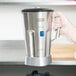 A person holding a Waring stainless steel blender jar and blending assembly.