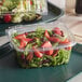 A table with two Dart ClearPac plastic containers, one with strawberries and one with salad.